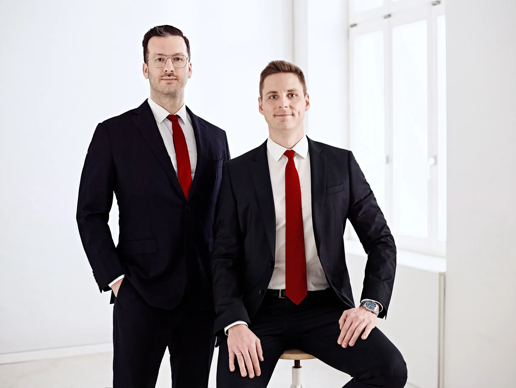 Johannes Schmidt and Deniz Schöne, founders and managing directors of Schmidt &amp; Schöne, in dark suits with red ties