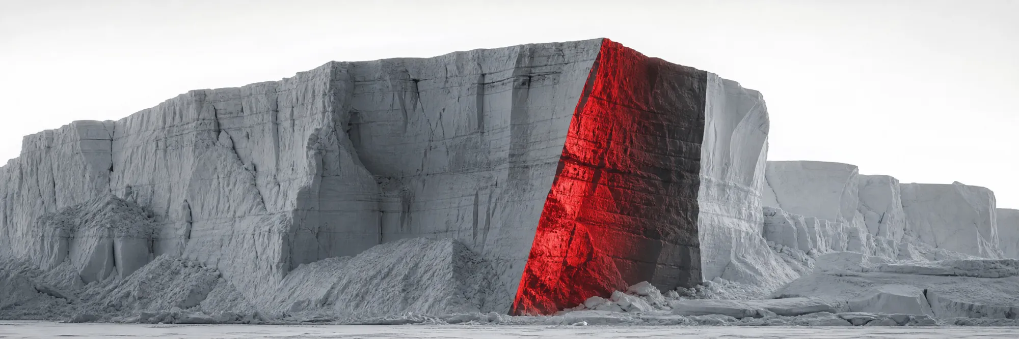Monochrome tabular iceberg, one cleaving face lit in red
